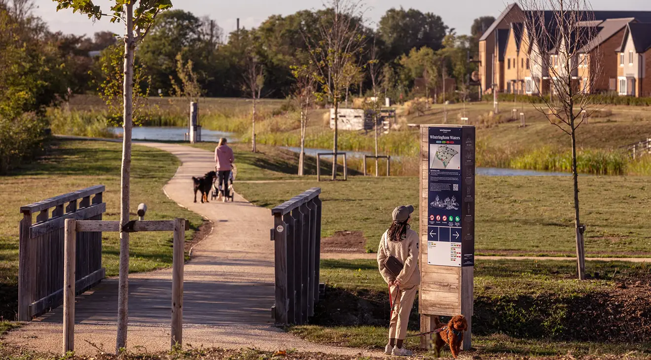 People are walking around the lakes and looking at the signage.